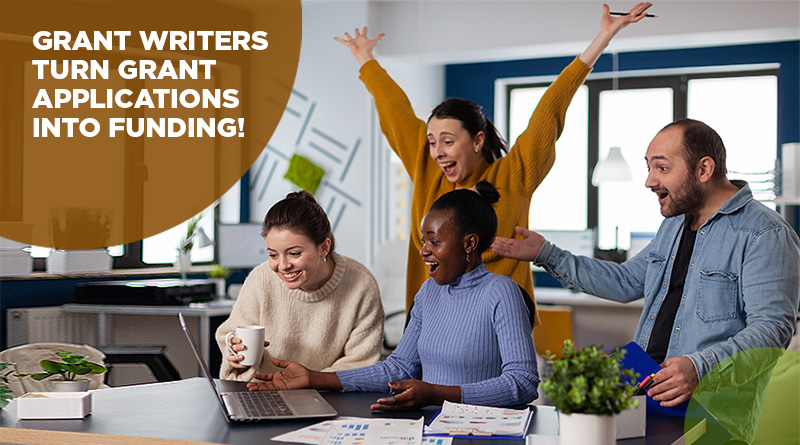 People gathered around a computer at work. The atmosphere is joyful and the women in the back has her arms raised in a cheer. They are happy they hired a professional grant writer and received grant funding.